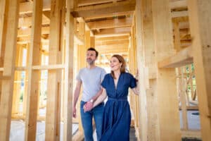 A man and woman walking through a house in the middle of construction.