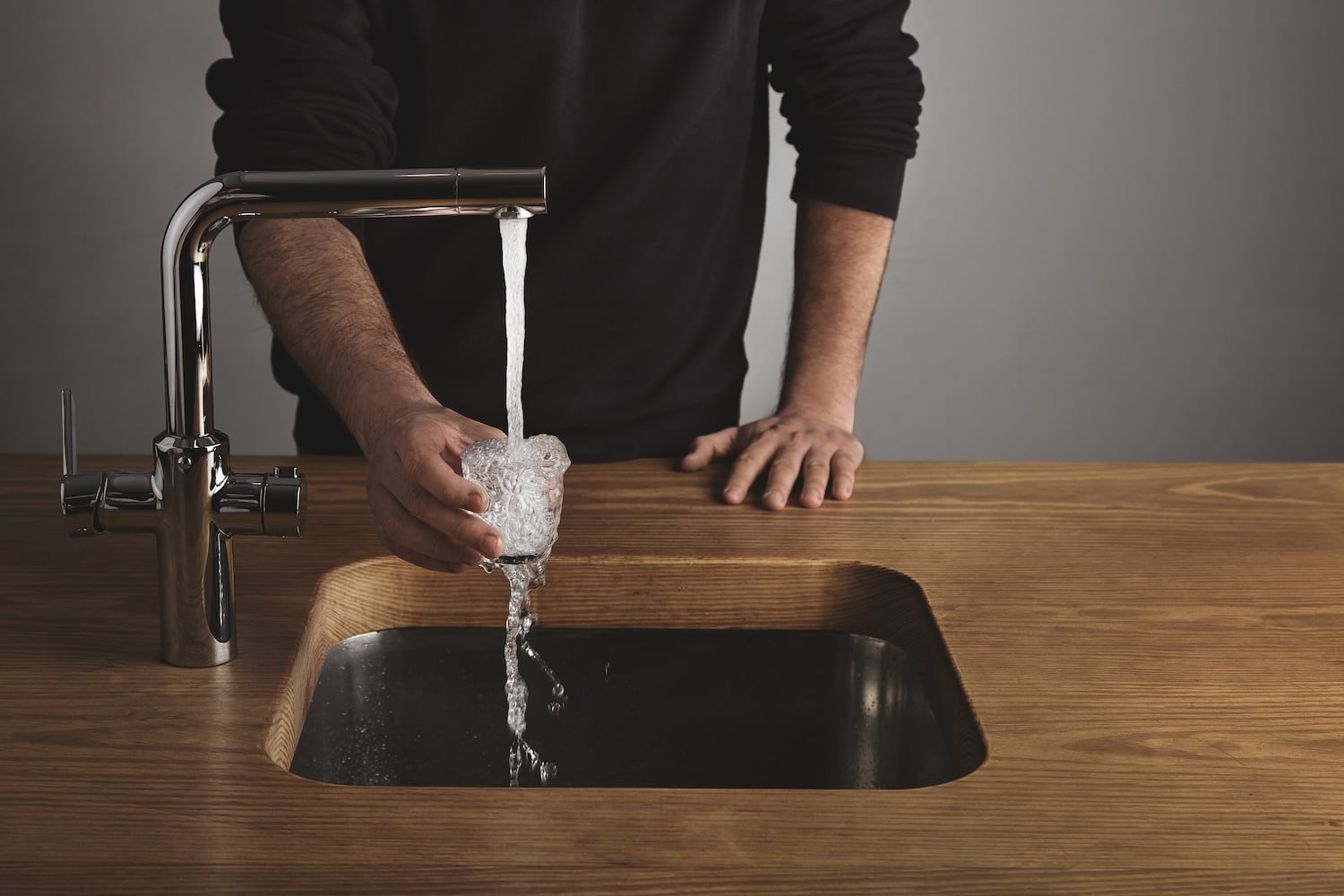 Man filling cup with water in sink